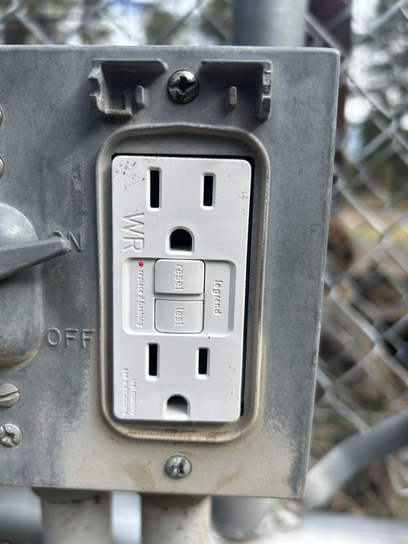 Weather-resistant GFCI outlet installed on an outdoor gate post in northern Arizona.